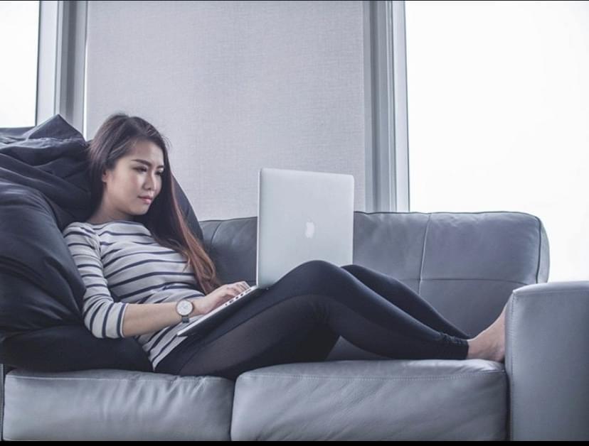 Woman sitting on couch looking at laptop